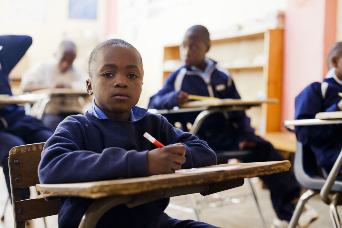 Un enfant haïtien écrit sur son bureau au sein de l'école Sainte-Hélène de notre organisation.