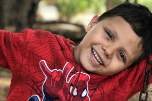 Un enfant parrainé sourit avec un sweatshirt spider-man.